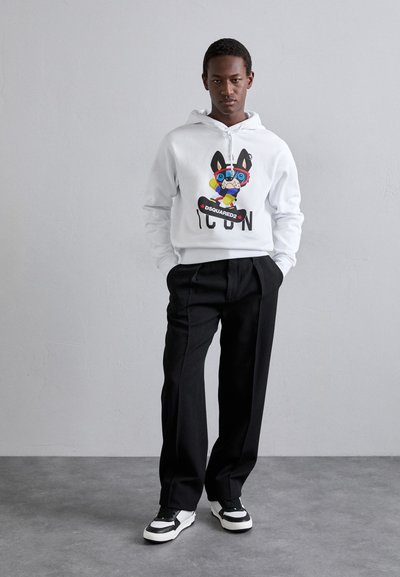 Weißer Hoodie mit grafischem Print eines Cartoon-Hundes und dem Text "ICON". Schwarze, locker sitzende Hose und schwarz-weiße Turnschuhe. Glatter Stoff, lässiger Stil.
