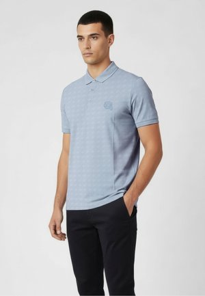 Polo bleu clair avec une texture à motif subtil, patte de boutonnage à deux boutons et un petit logo sur la poitrine gauche. Manches courtes, coupe classique.