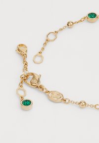 Gouden armband met gekoppelde achthoekige vormen, een kreeftslot, groene edelsteenaccenten en ronde kralen langs de ketting.