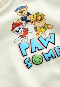 Trois chiots animés en tenues de pompier, de policier et de construction au-dessus du texte coloré "PAW SOME" avec un visage souriant vert.