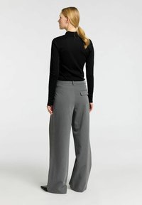 Zwarte lange mouwen top gecombineerd met grijze wijde broek, met een achterzak en een soepele stofstructuur.