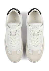 Pár bílých a béžových tenisek s černými akcenty na patě, bílými tkaničkami a perforovanými detaily v oblasti špičky a jazyka.