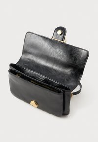 Clutch de couro preto com aba aberta, revelando dois compartimentos e um fecho de clasp dourado sobre um fundo branco.