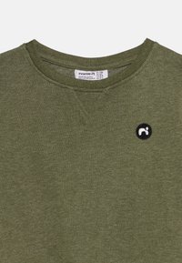 Olive green sweatshirt with ribbed round neckline, featuring a small black circular logo patch. Soft fabric texture with a casual design.
