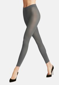 Leggings grigi con una texture liscia e elastica, vita alta e forma aderente, abbinati a scarpe con tacchi alti nere.