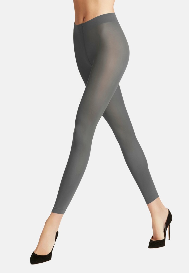 Leggings grigi con una texture liscia e elastica, vita alta e forma aderente, abbinati a scarpe con tacchi alti nere.
