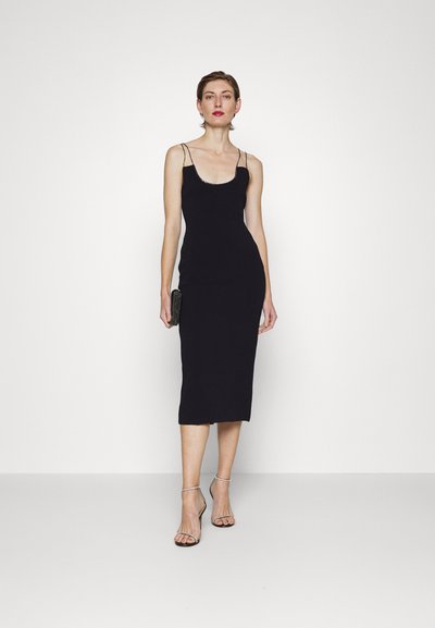 Must värvi, pehme voodriga kleit õhukeste rihmadega, põlvepikkune, ribakujulise tekstuuriga, stiilitud metallik sandaalide ja väikese musta käekotiga.