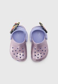 Lila glittriga träskor med ventilationshål, med en svart fjärilsformad dekoration. Tillverkade av lätt material med en texturerad insida.