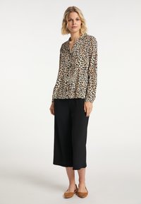 Blus med leopardmönster, krage, långa ärmar och lätt tyg. I kombination med svarta vida byxor och bruna ballerinaskor.