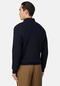 Světlý, texturovaný pletený svetr námořnické modři s límcem a žebrovanými manžetami. Tvarovaný střih, jednobarevný a minimalistický design.