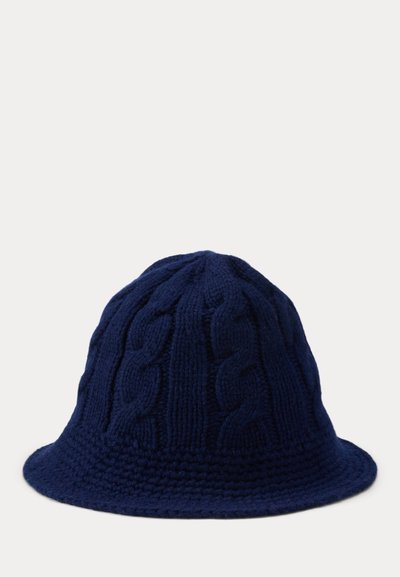 Tumši zils tamborēts spaiņa cepure ar pīto rakstu, mīkstu tekstūru un plašu, apaļu malu. Piemērots ikdienas valkāšanai.