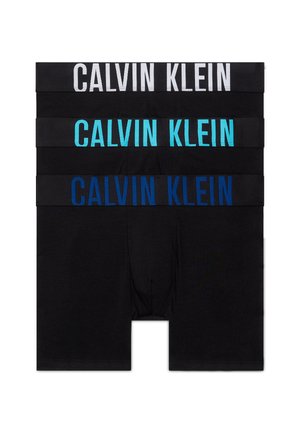 Tres pares de bóxers negros apilados, cada uno con una cinturilla ancha que muestra "Calvin Klein" en texto blanco, azul claro y azul oscuro.