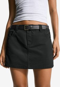 Black denim mini skirt with a fitted design, featuring a front pocket, belt loops, and a black leather belt with a gold buckle accent.