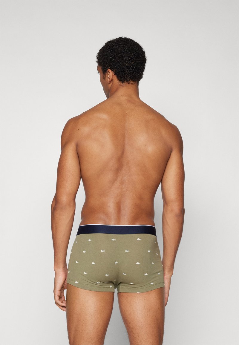 Zielone bawełniane slipy z białym wzorem logo, granatowa talia, dopasowany krój i gładka tekstura, pokazane od tyłu.