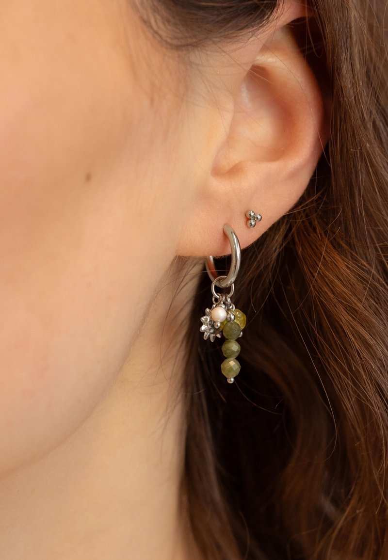Orecchino a cerchio d'argento con perline di pietra verde e una perla, decorato con piccoli accenti floreali. Un altro piccolo orecchino a perno nell'orecchio.