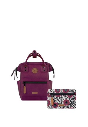 Purple backpack with front zipper pocket and two handles, next to a floral patterned pouch with a zipper, both branded Cabaia.