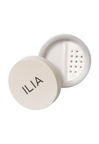 ILIA transparent puder i en rund vit behållare med en öppning för dispensering. Slät puder med en fin konsistens och en stilren design.