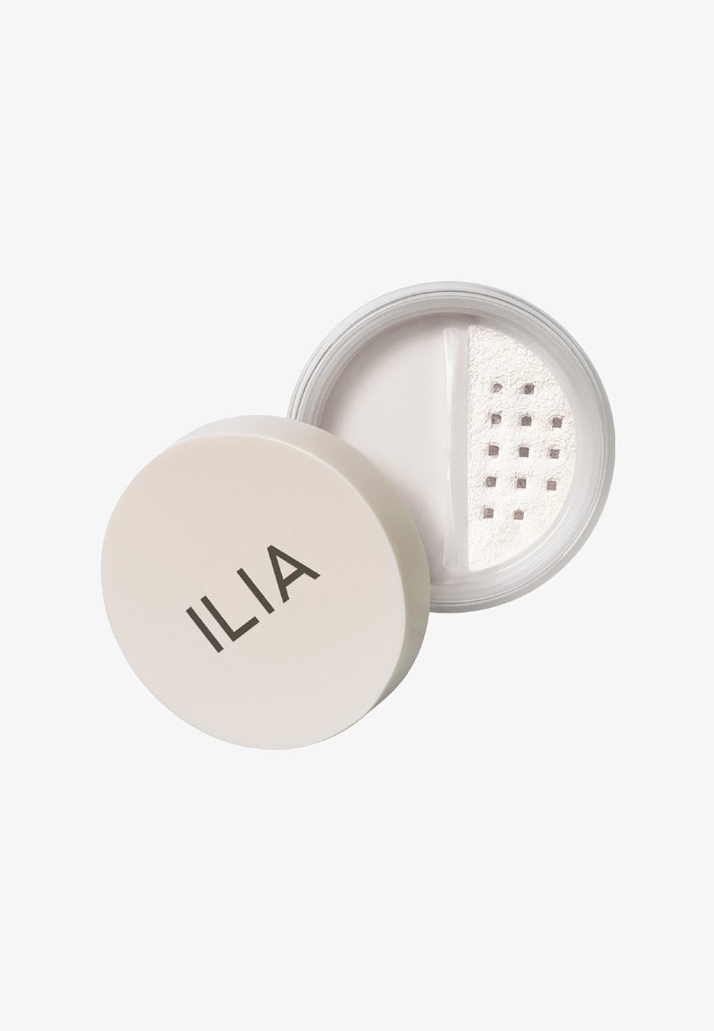 ILIA transparent puder i en rund vit behållare med en öppning för dispensering. Slät puder med en fin konsistens och en stilren design.