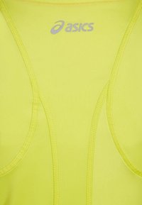 Top atlético de color amarillo neón con un tejido suave y elástico. Presenta un escote redondeado y tirantes finos. Logotipo de Asics en plata ubicado sobre el escote.