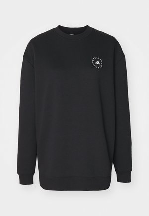 Svart genser laget av myk stoff, med rund hals og lange ermer. Den har et hvitt logo-design på forsiden.