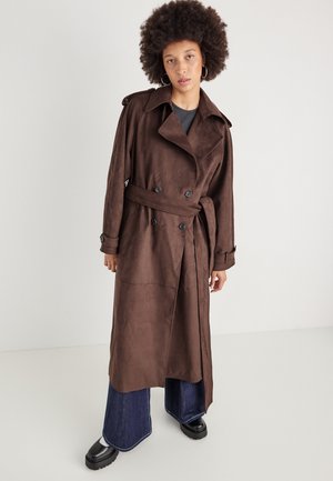 Cappotto trench in finta suede marrone con cintura, design doppiopetto, ampie revers e dettagli con bottoni. Abbinato a jeans svasati e stivali con plateau.