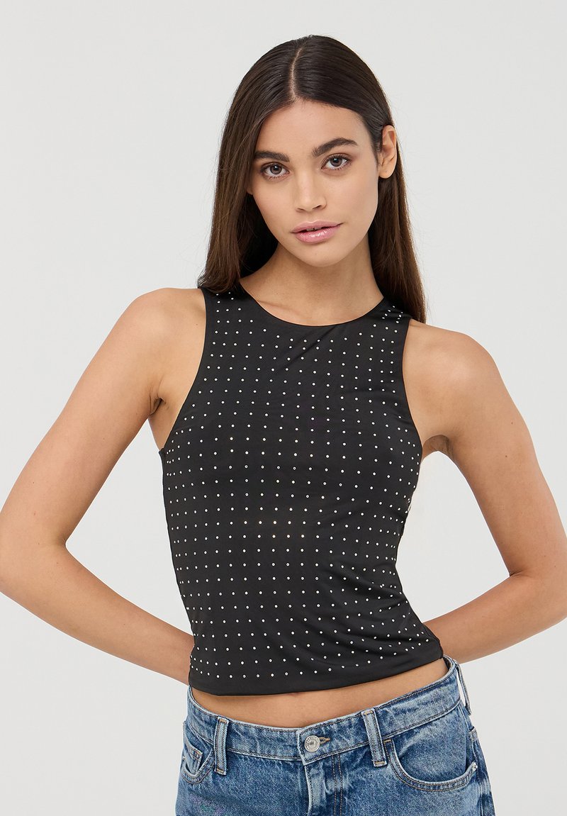 Czarny, bezrękawnikowy top typu crop o dopasowanym fasonie, z małymi metalicznymi ćwiekami ułożonymi w kropkowy wzór na przodzie.