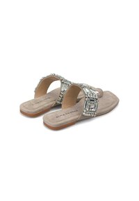 Sandali in suede beige con decorazioni di cristalli sui cinturini, dotati di suola piatta e design aperto sul retro, etichettati "ALMA EN PENA."