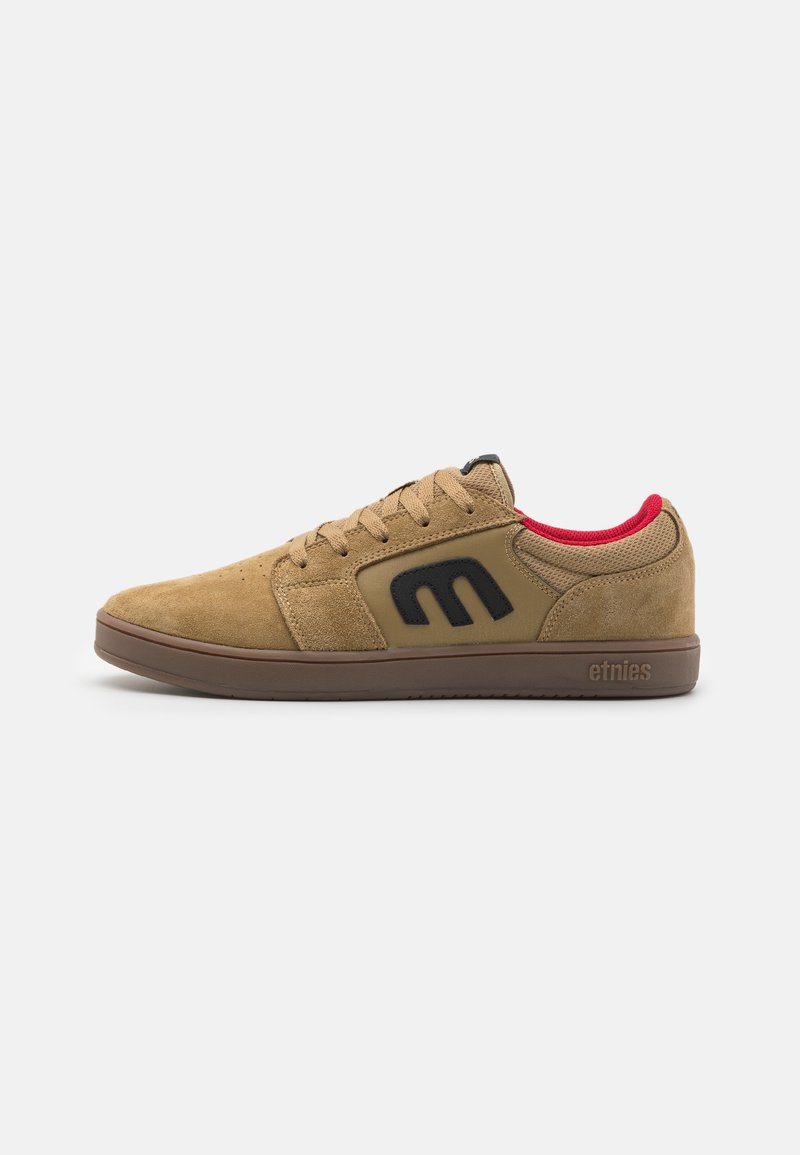 Tenis din suede bej cu logo negru, detalii interioare roșii și talpă din cauciuc. Prezintă șireturi rotunde și un guler căptușit pentru confort.