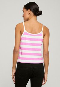 Roze en witte gestreepte tanktop met spaghetti-bandjes, met een aangesloten ontwerp en een zachte katoen structuur, gedragen met donkere jeans.