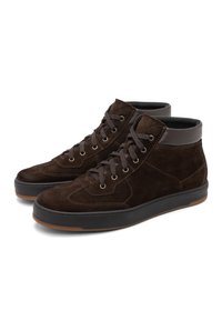 Une paire de baskets montantes en suède marron avec des lacets marron foncé, des semelles intermédiaires noires et des semelles extérieures couleur gomme sur fond blanc.
