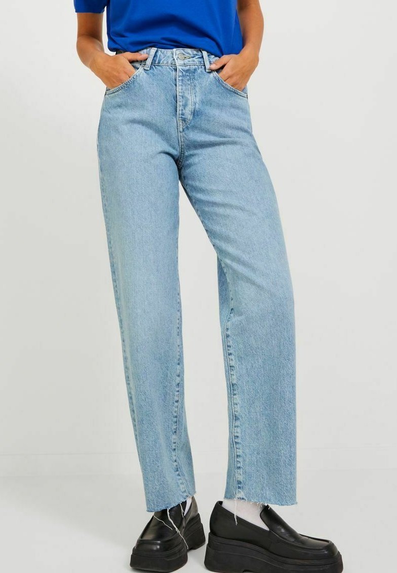 Ljust blå högmidjade jeans med rak ben, rå kant och lätt blekning. Matchas med svarta plattformsskor.