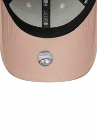 Baseballkappe aus weichem pinkfarbenem Stoff mit einem schwarzen Schirm, der einen runden Baseball-Logo-Aufkleber auf dem Schirm präsentiert.