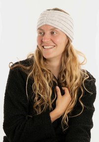 Fascia per la testa lavorata a maglia di un grigio chiaro, con ampie strisce verticali e un motivo testurizzato, indossata da una persona con capelli lunghi e mossi, su sfondo bianco.