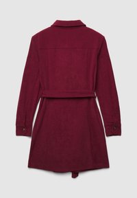 Cappotto in velluto a coste color bordeaux con maniche lunghe, colletto e cintura da annodare. Presenta un tessuto strutturato e polsini con bottoni. Vista posteriore in mostra.