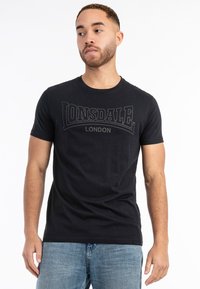 Juodas trumpas rankovėmis marškinėliai, pagaminti iš medvilnės, su grafiniu "LONSDALE LONDON" logotipu subtiliu tonu per krūtinę.