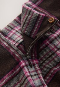 Brown and plaid zippered jacket featuring shades of pink, grey, and white in a checkered pattern; soft texture with a button accent.
