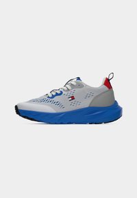 Αθλητικά παπούτσια με γκρι άνω μέρος από δίχτυ, μπλε σόλα και γκρι λεπτομέρειες. Διαθέτουν λευκά κορδόνια και κόκκινες, μπλε και λογότυπο λεπτομέρειες κοντά στη φτέρνα.