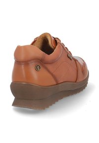 Zapatilla de cuero marrón con un diseño de bajo perfil, suela de goma texturizada, puntera redonda y un acento metálico decorativo cerca del talón.