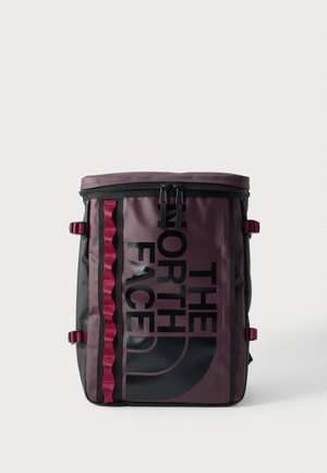 Zaino The North Face alto rettangolare bordeaux e nero con cerniera superiore e logo nero verticale sul pannello anteriore.