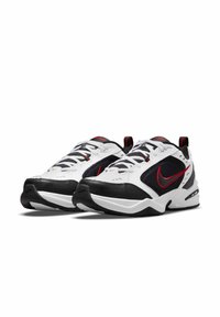 Scarpe da ginnastica bianche e nere con il logo Nike rosso, caratterizzate da una tomaia in mesh, colletto imbottito e suola in gomma texturizzata.