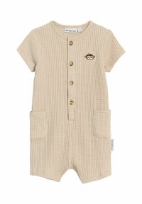 Beige short-sleeve romper met een gestructureerd wafelpatroon, voorzien van een knoopsluiting aan de voorkant, twee zakken en een kleine geborduurde aapdetail.