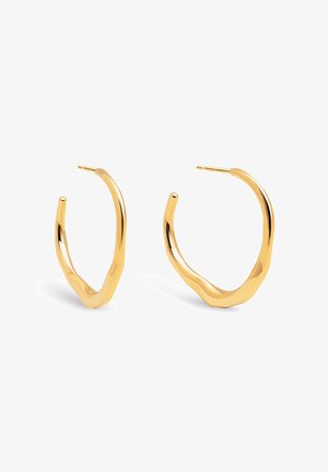 Boucles d'oreilles en métal doré avec un design ondulé. Les boucles affichent une finition polie et une forme ouverte avec une surface texturée.