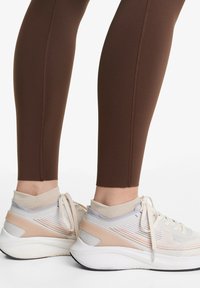Bruna leggings med texturerad sömnad i kombination med lätta, flerfärgade sportskor med ribbat ankeldesign och vadderad sula.