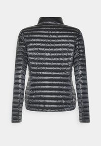 Black quilted puffer jacket with a stand collar and long sleeves. Features a textured surface and a logo tag near the hem. Lightweight design.