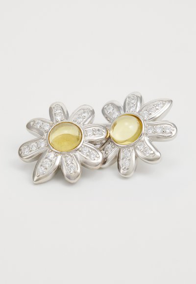 Orecchini a forma di fiore in argento con pietre gialle al centro, circondate da gemme trasparenti lungo i petali.