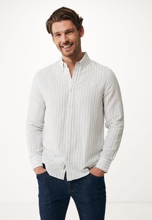 Licht gestreepte button-up blouse in wit en lichtblauw, lange mouwen met verstelbare manchetten, gecombineerd met donkere jeans, gladde textuur.