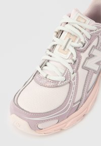 Világos rózsaszín és levendula sportcipő fehér fűzőkkel, texturált szövettel és márkajelzésekkel az orrán és az oldalán, felülről, elölről nézve.