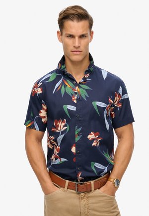 Camisa de flores de manga corta en navy, que presenta grandes flores rojas y blancas con hojas verdes, cierre de botones y una textura suave.