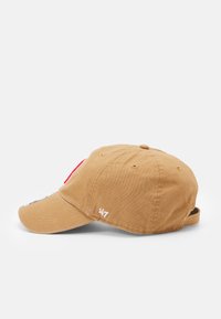 Beige Baumwollmütze mit gebogenem Schirm, verstellbarem Riemen, gesticktem Logo und einem Patch mit roten und grauen Details auf der Vorderseite.
