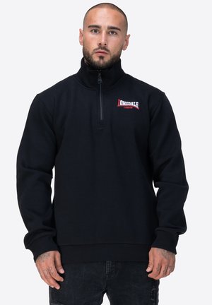 Czarny polarowy sweter z zamkiem błyskawicznym i wysokim kołnierzem. Posiada logo Donsdale w kolorze czerwonym oraz ściągacze na dole i przy mankietach dla dodatkowej tekstury.
